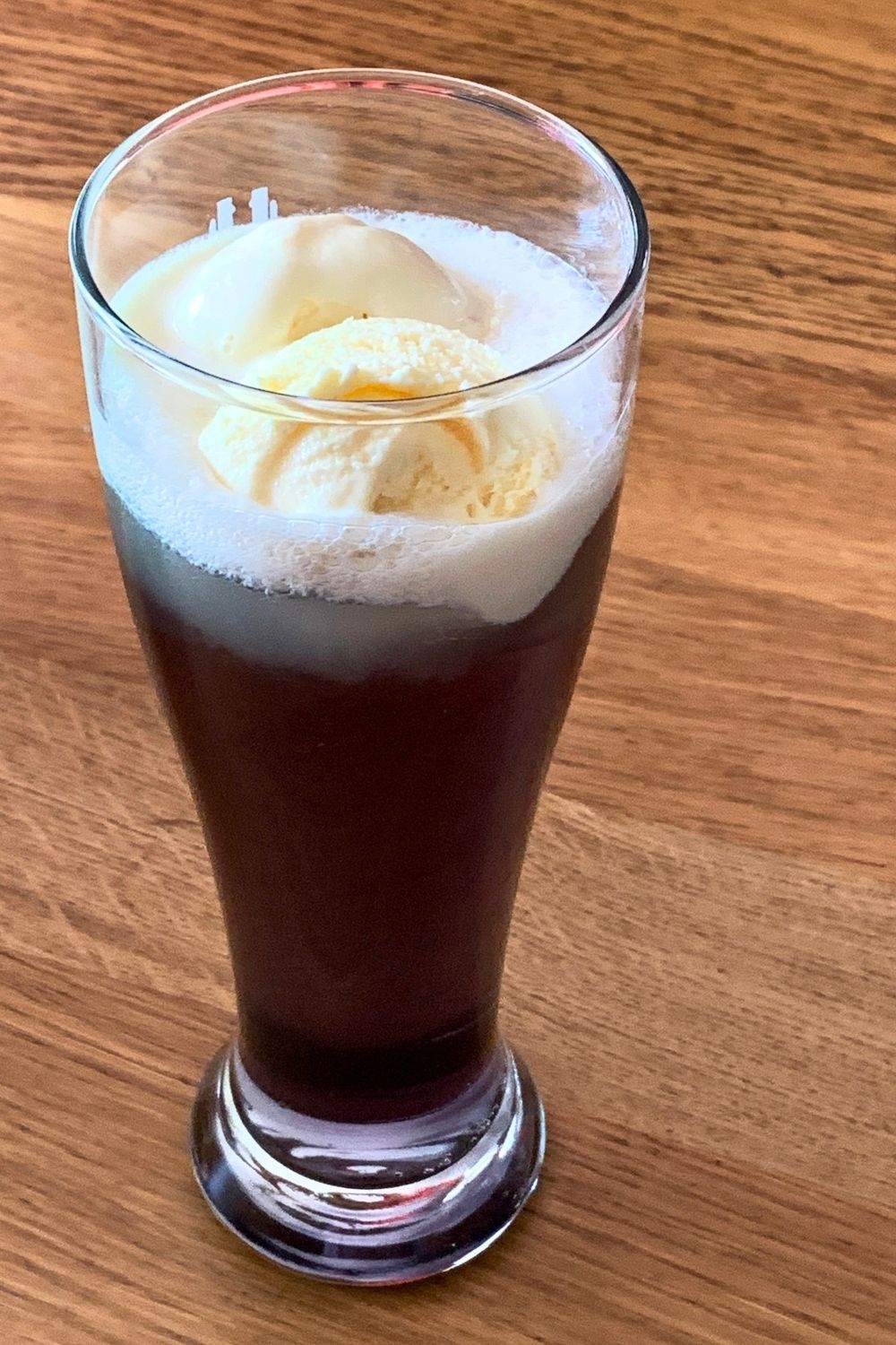 Vanilla ice cream floating at the top of a glass of dark purple soda.