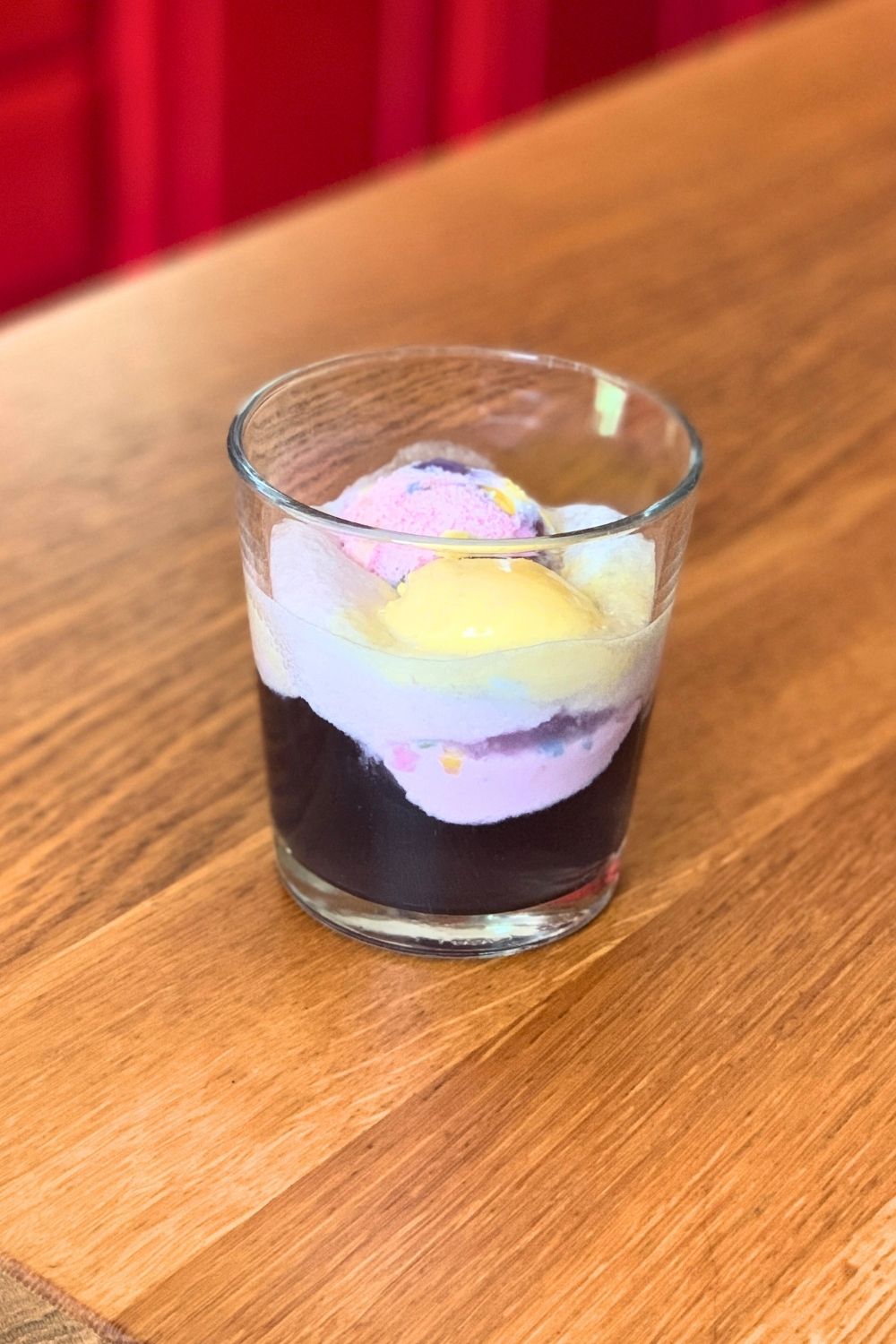 Rainbow ice cream on top of a glass of purple soda.