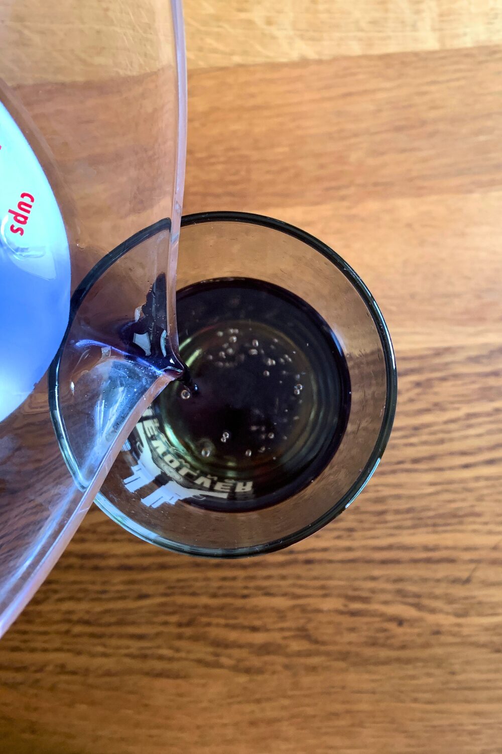 Pouring purple syrup into a glass.