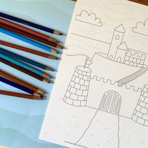 Printable sandcastle coloring page beside a handful of colored pencils.