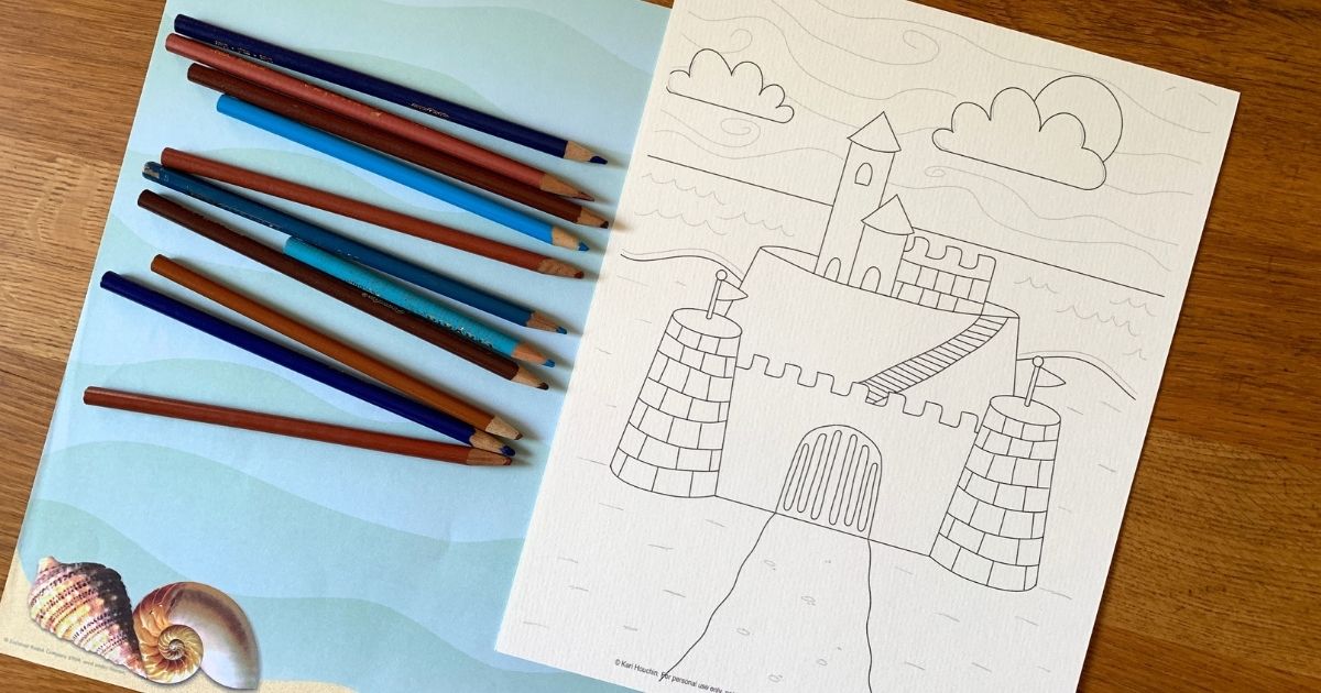 Printable sandcastle coloring page beside a handful of colored pencils.