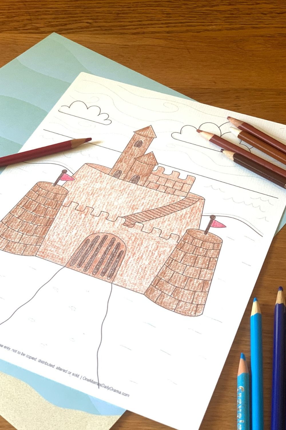 Using colored pencils to color a sandcastle picture in shades of brown.
