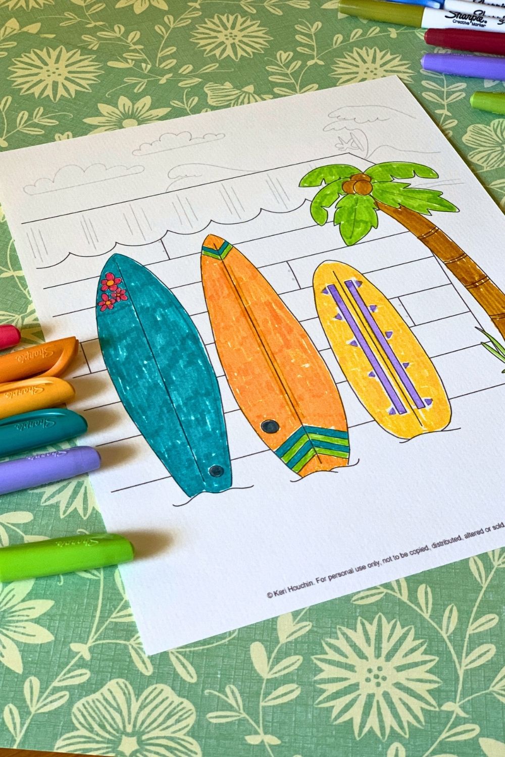 Coloring a picture of surfboards with blue, orange, and yellow markers.