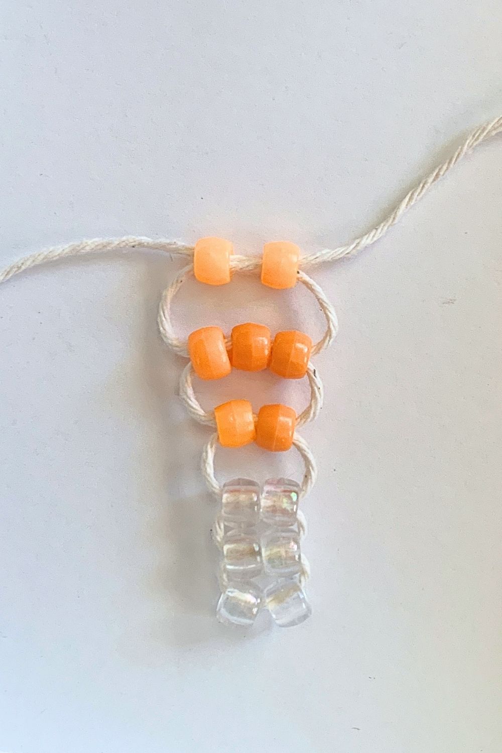 Weaving rows of 2, 3, and 2 orange pony beads.