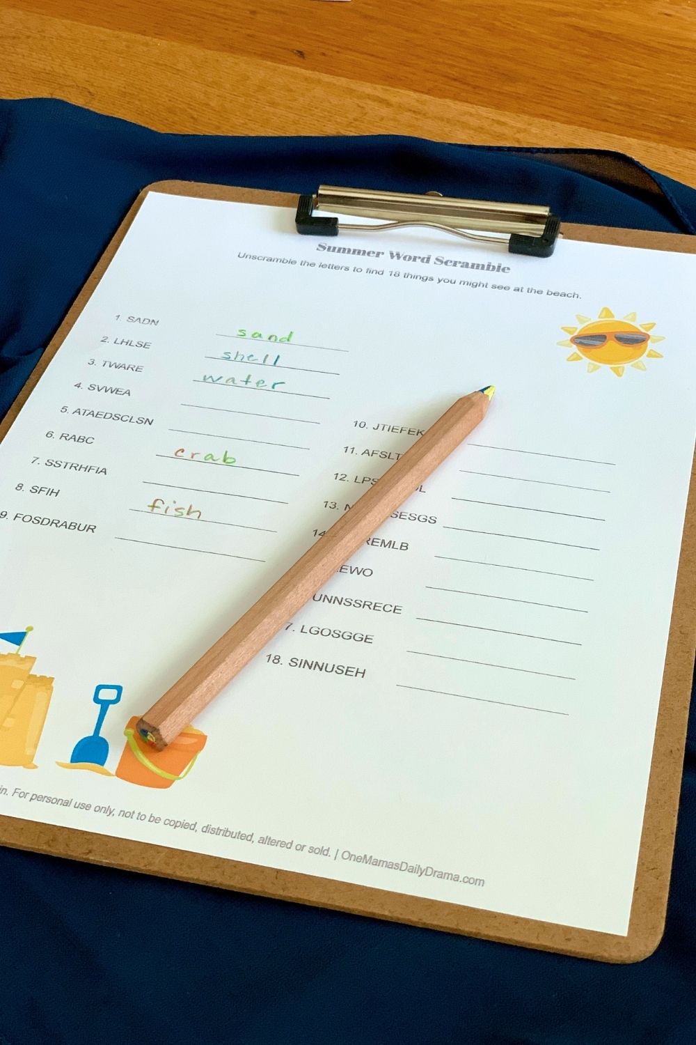 A colored pencil on top of the worksheet with answers filled in for sand, shell, water, crab, and fish.