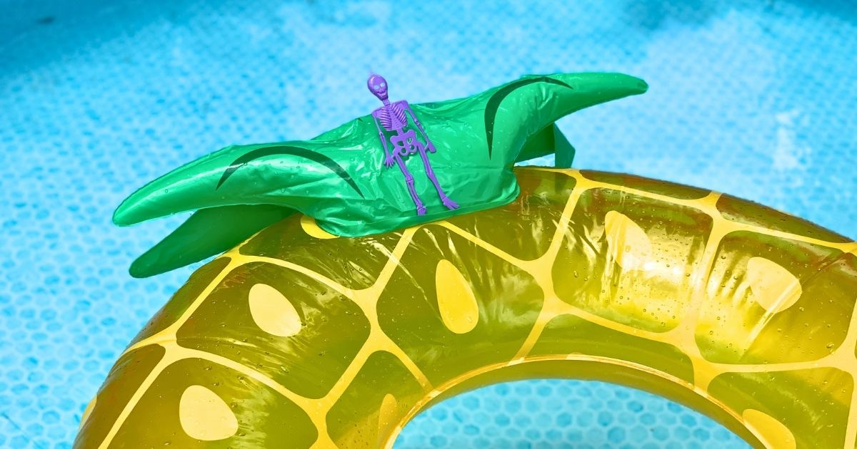 Tiny plastic skeleton laying on a pineapple pool float.