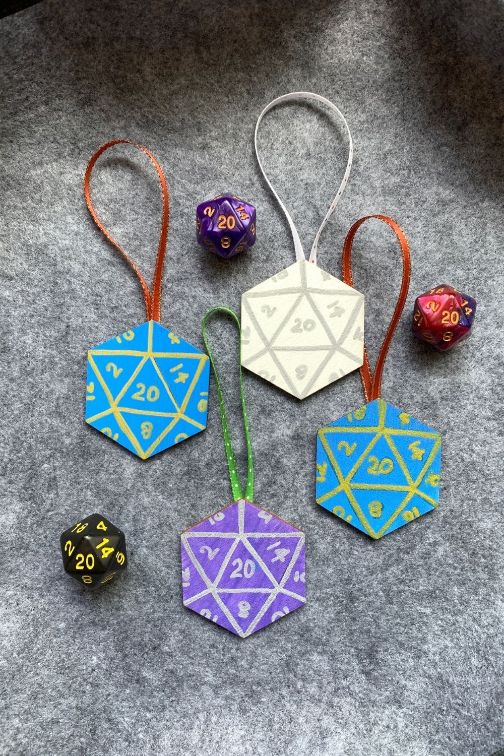 D&D 20-sided dice ornaments made from painting wood hexagons in blue, purple, and white with metallic marker lines and numbers.