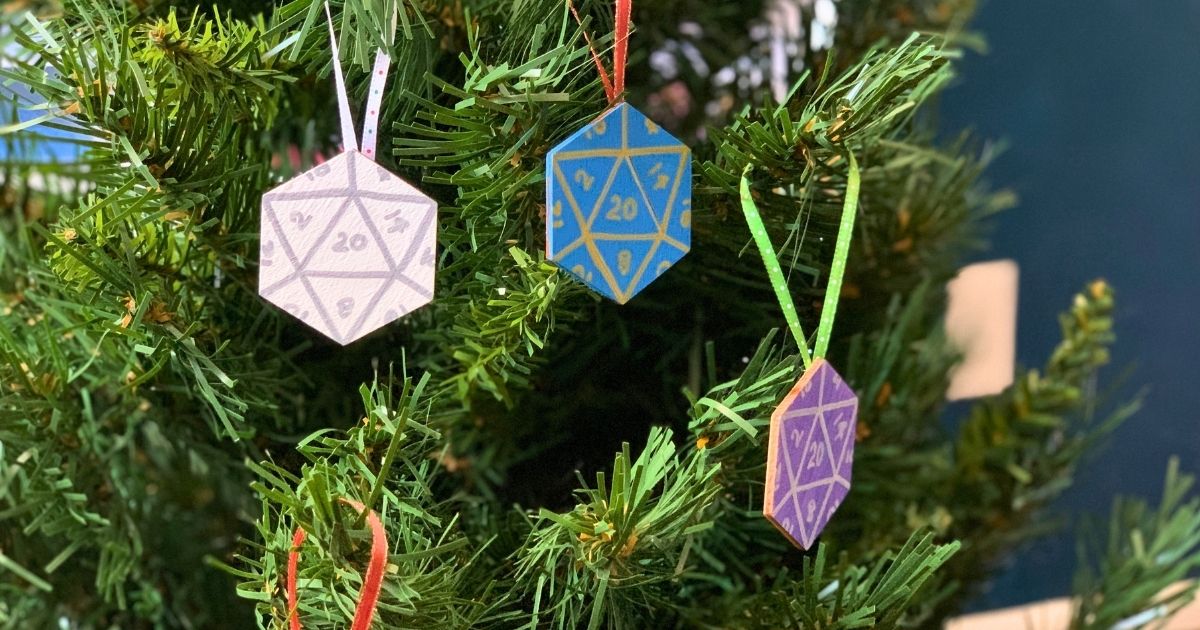 A Christmas tree with 3 hexagon ornaments painted to look like 20-sided dice.