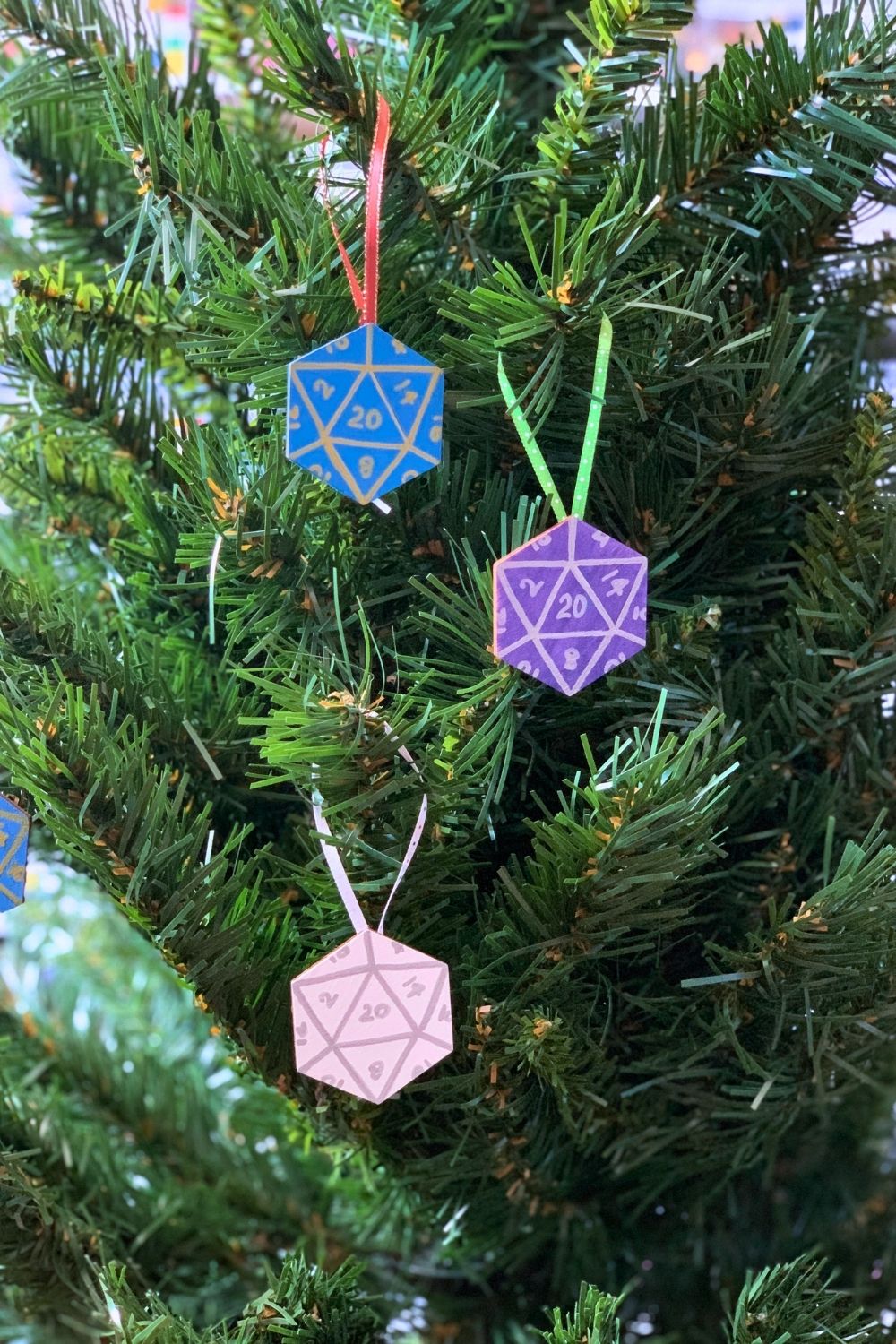 A Christmas tree with 3 hexagon ornaments painted to look like 20-sided dice.