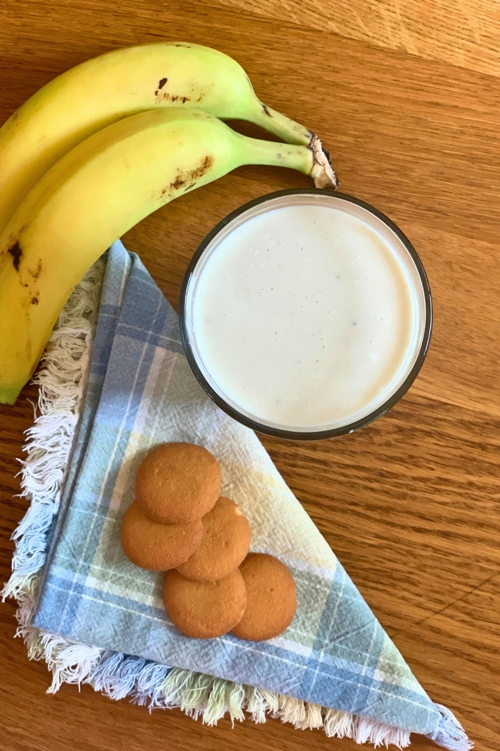 A glass of smoothie beside a stack of 5 vanilla wafer cookies.