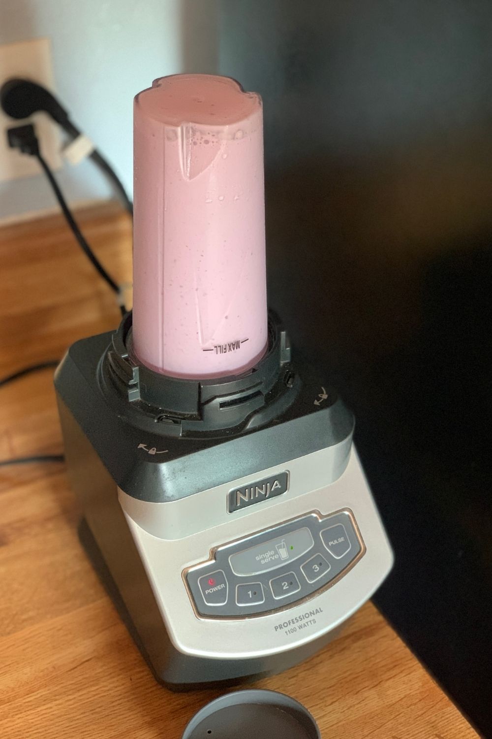 A full smoothie cup on a blender base.