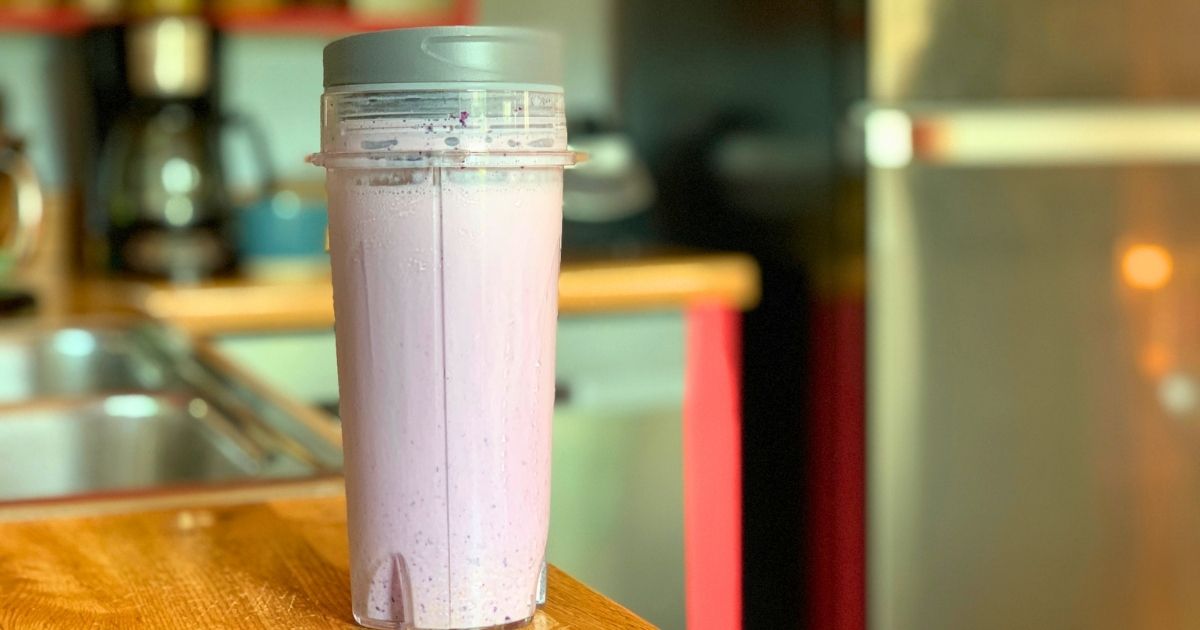 A pale purple blueberry pie smoothie in a blender cup.