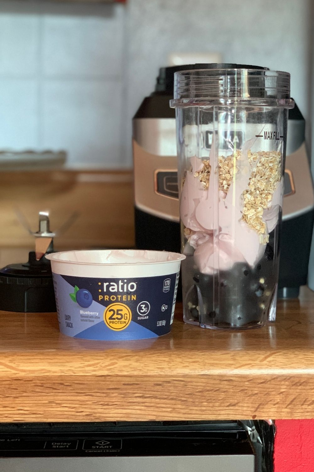 A container of Ratio protein yogurt in blueberry beside a blender.