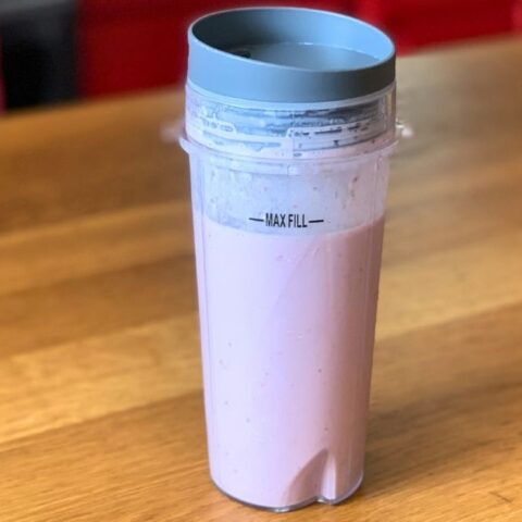 A pink cherry pie smoothie in a plastic blender cup with a lid.