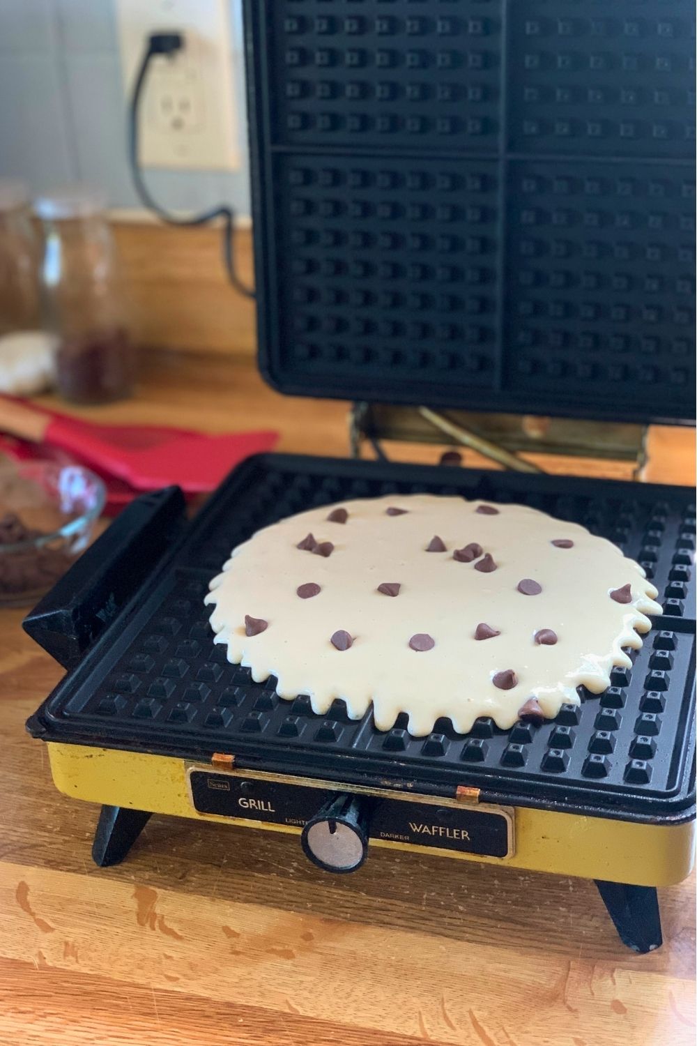 Waffle batter on a hot iron sprinkled with chocolate chips before closing.