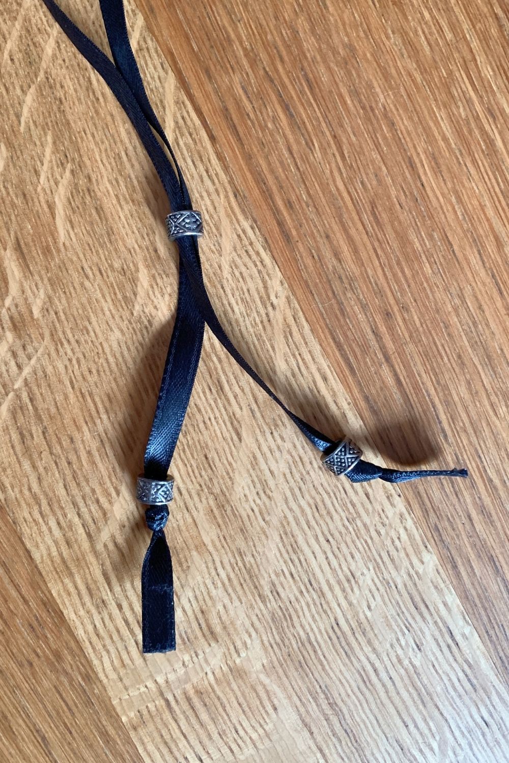 Black ribbon with beads making the ends into a drawstring Y.