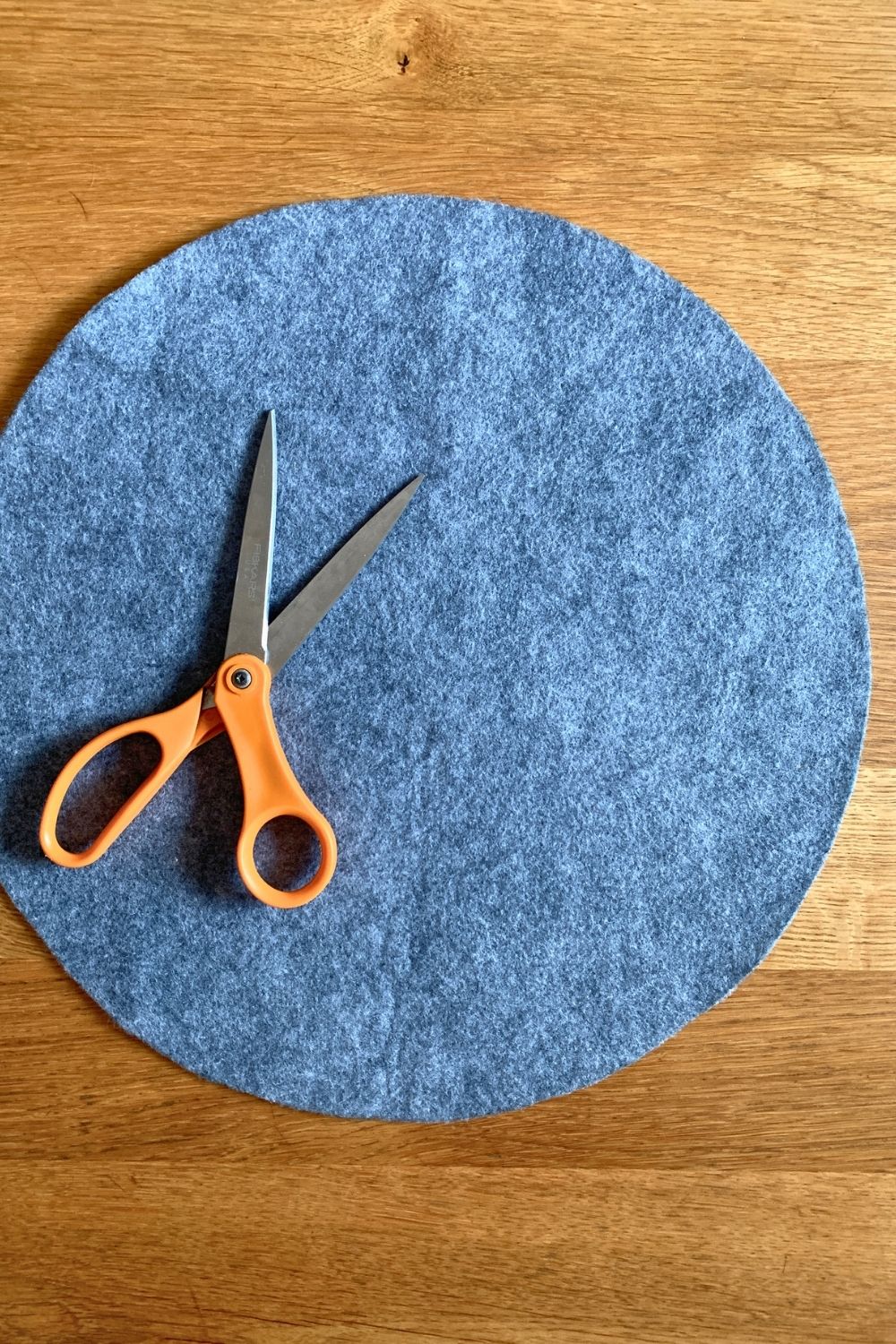 A gray felt circle beside a pair of scissors.
