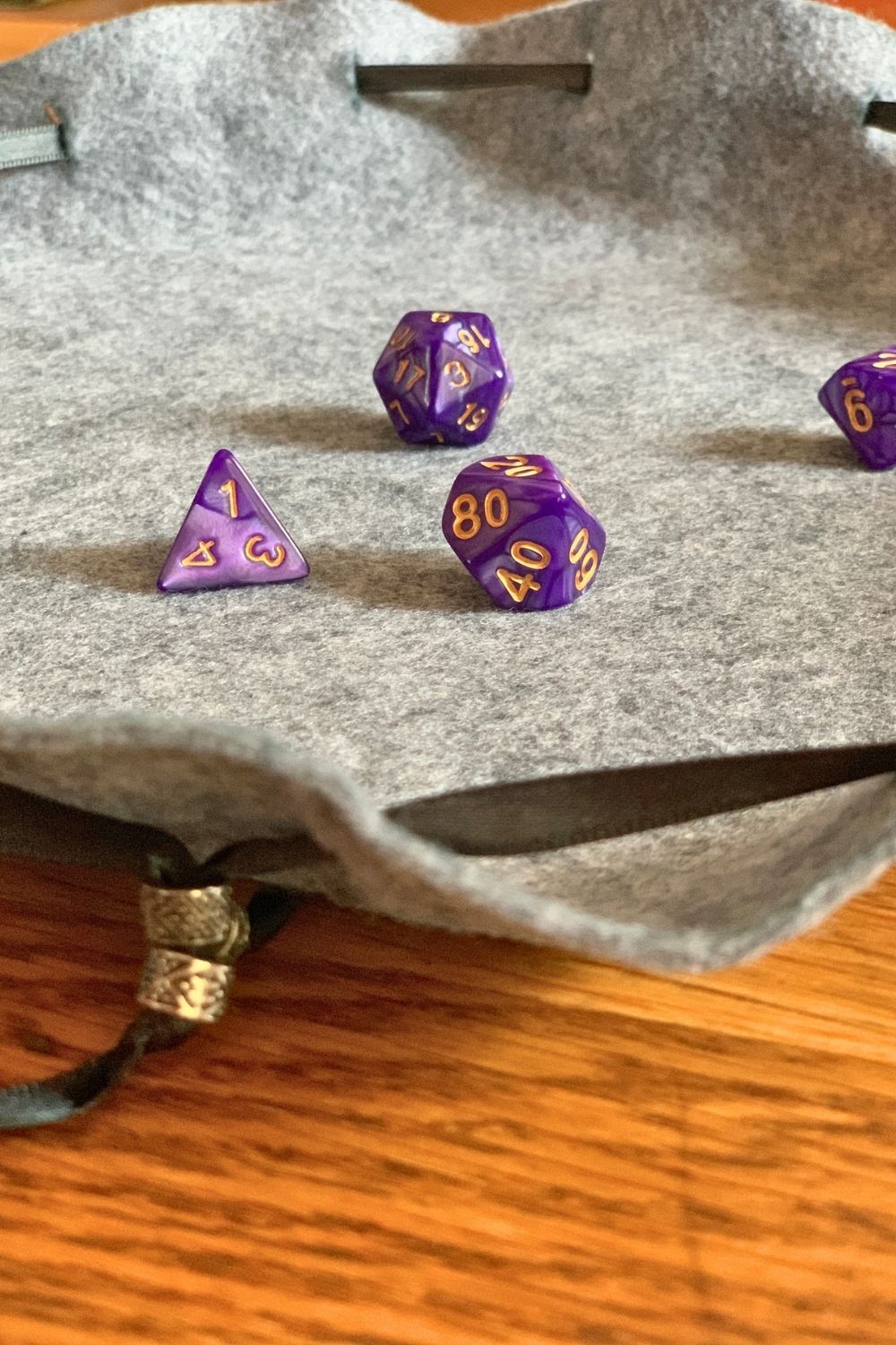 Closeup of purple D&D dice on an open felt bag used as a rolling mat.