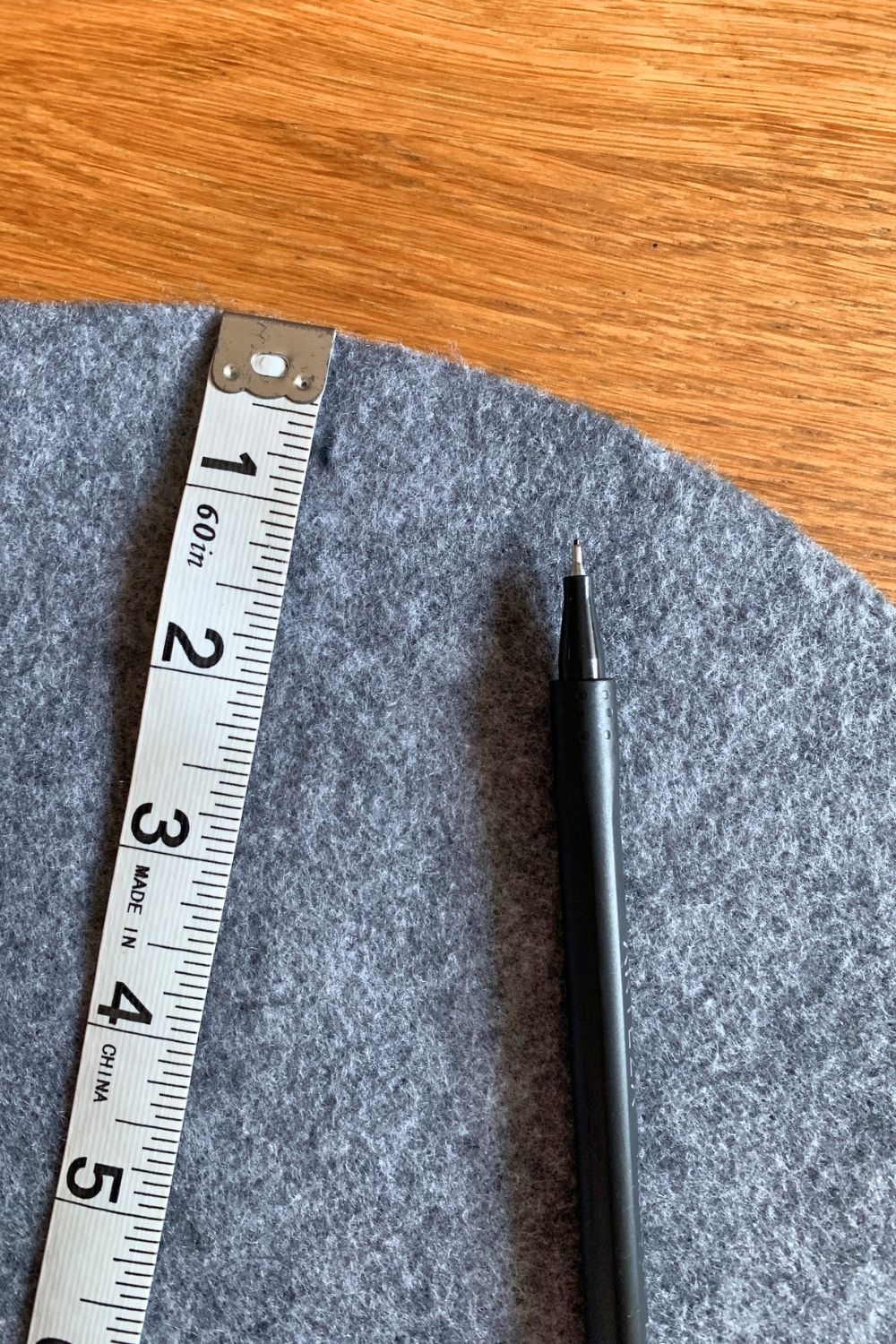 A soft tape measure on top of gray felt with a black pen mark at half an inch.
