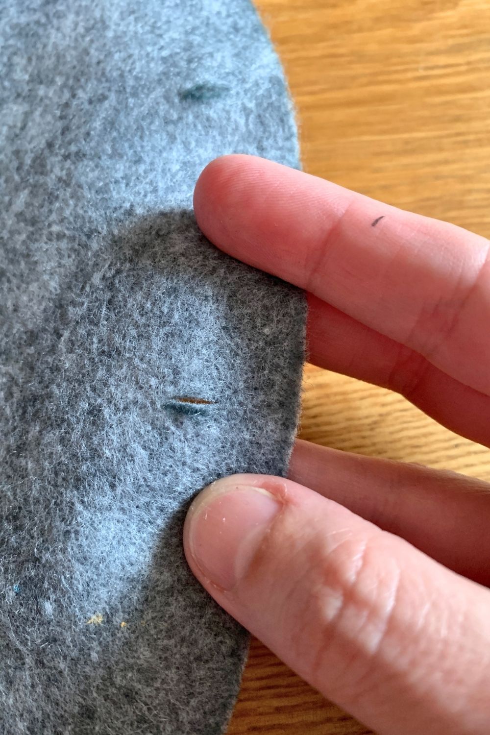 A closeup of quarter-inch slits cut around the edge of a felt circle.