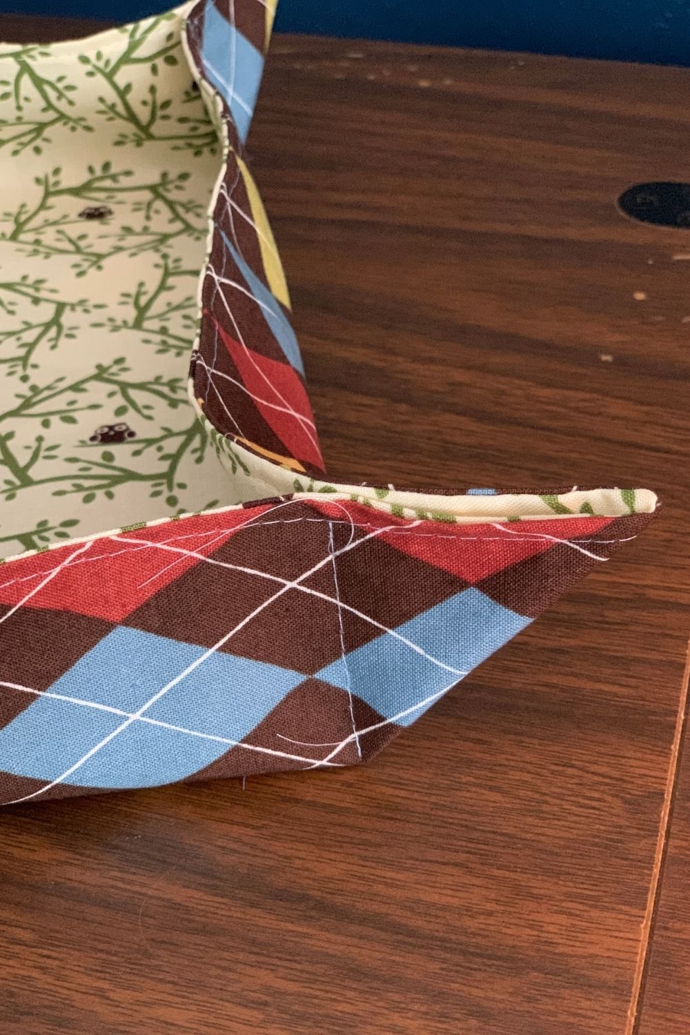 A square fabric tray with stitched triangle corners.