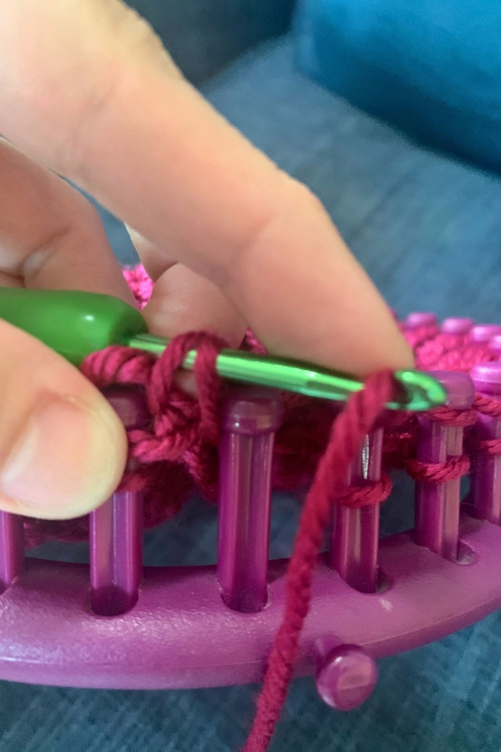 Yarn on a crochet hook being pulled through a knitted loop.