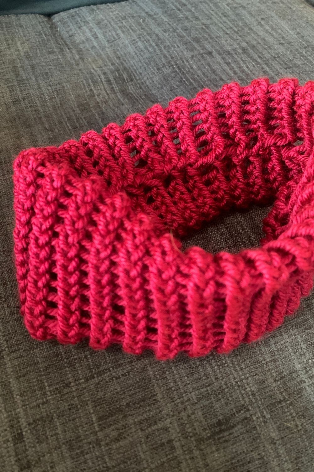 A fuchsia loom knit headband with a seam on the inside.