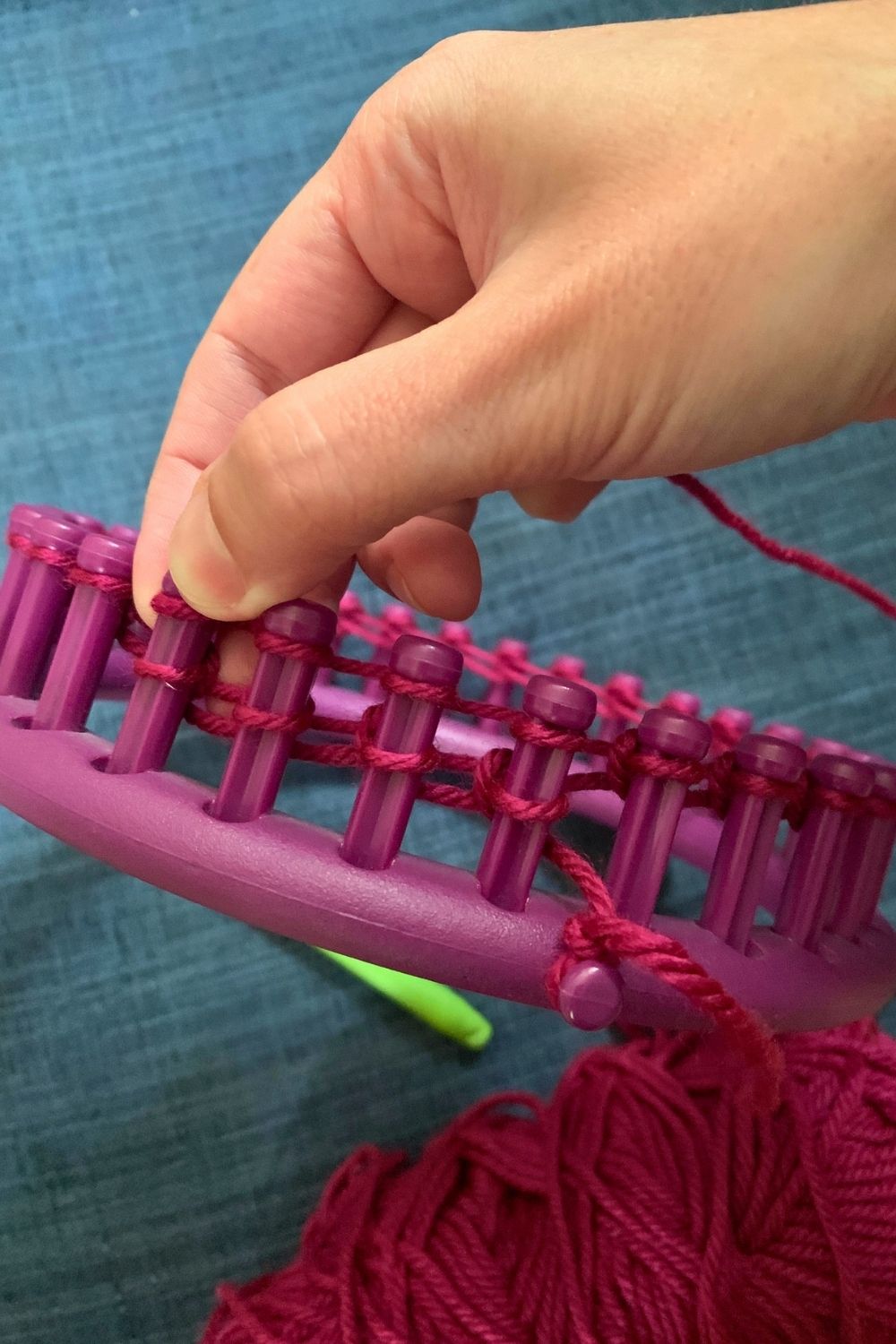 Wrapping the next row of yarn around the loom pegs.