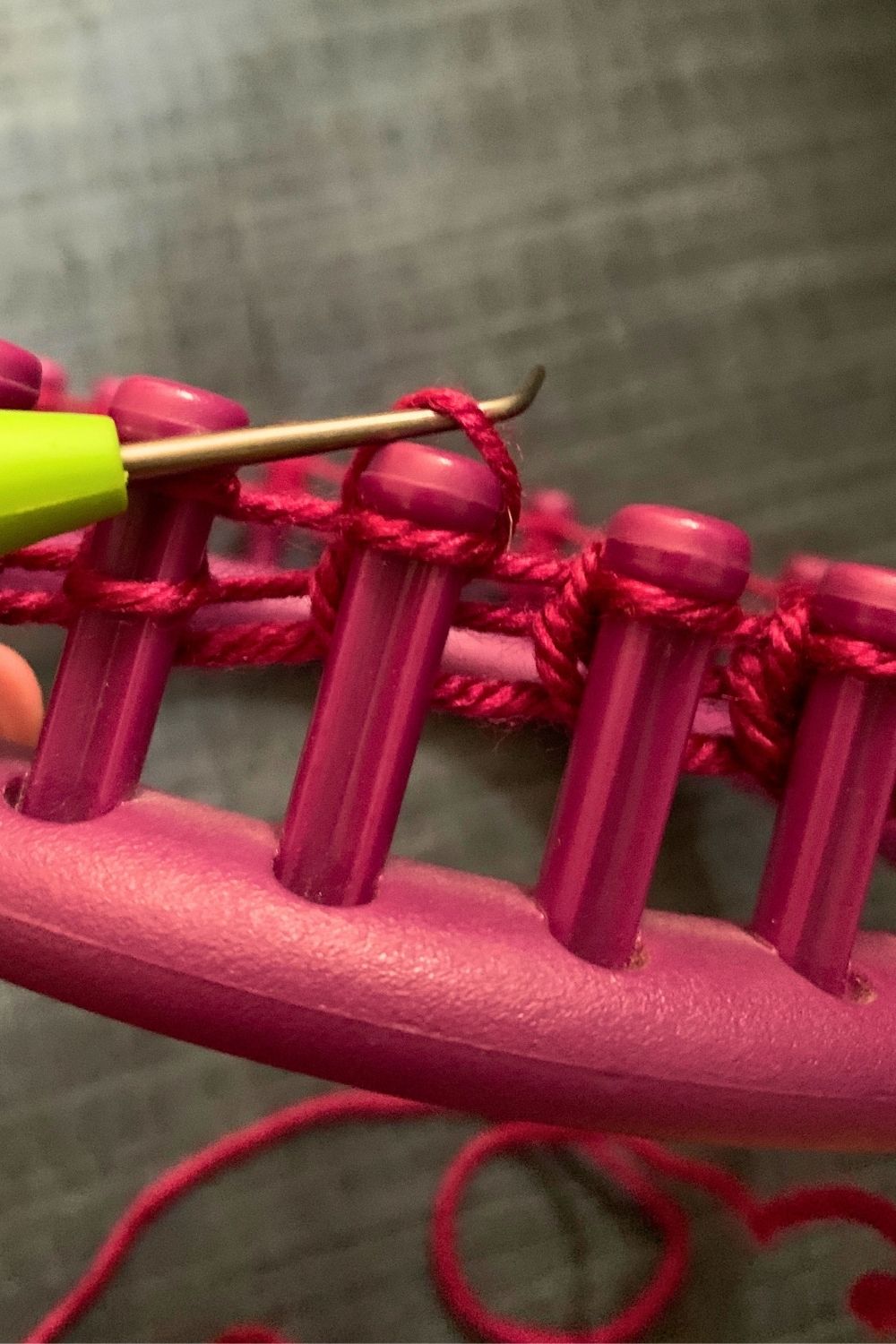 Knitting the bottom loops over the top loops on the loom.