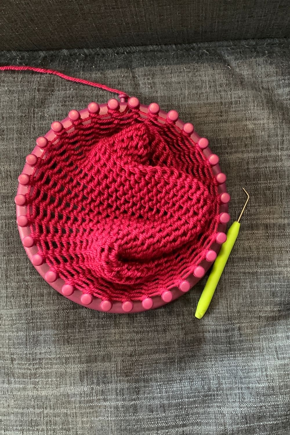 A knitting loom with a large amount of knitted yarn in the center.