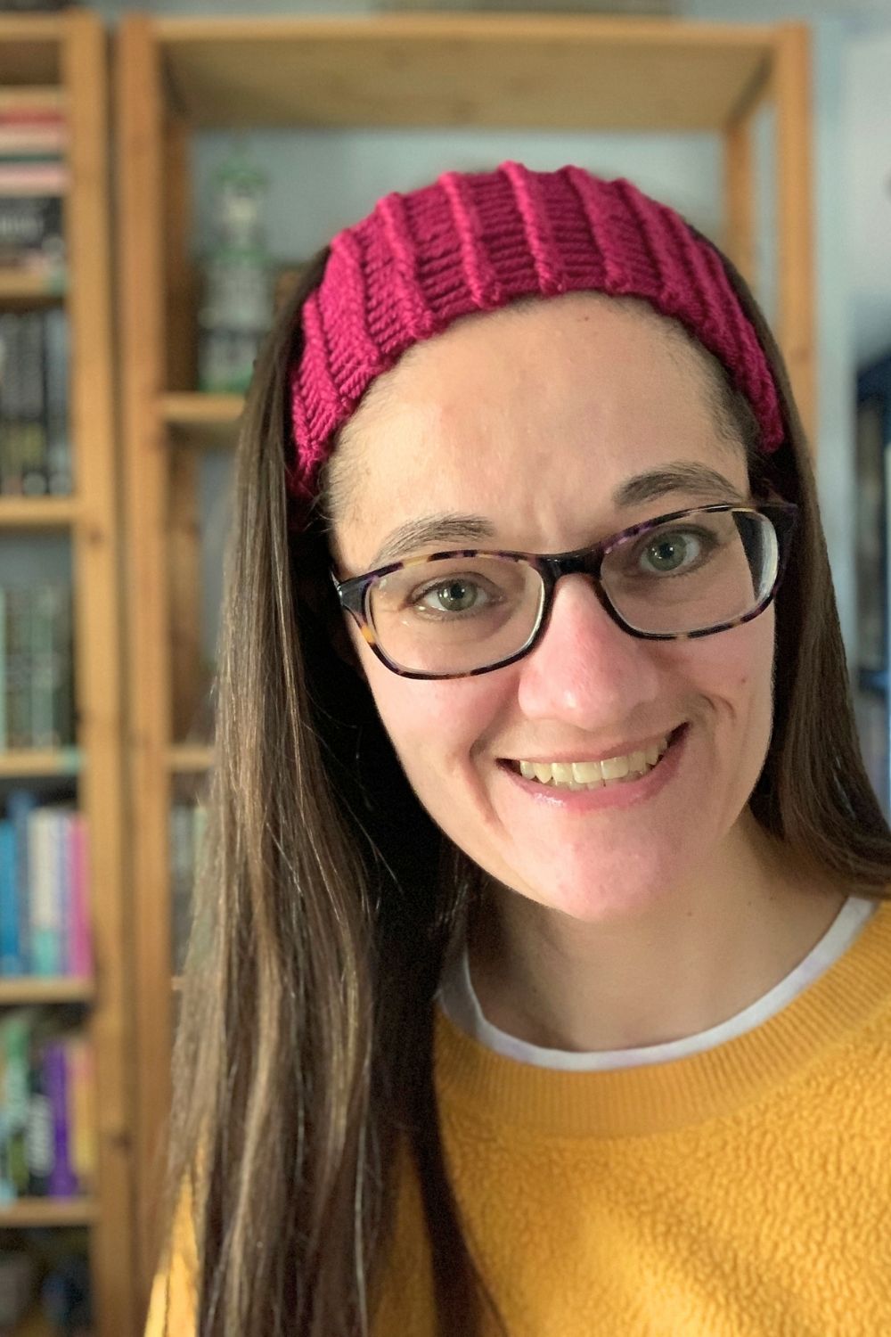 A woman with long hair and eyeglasses wearing a fuchsia loom-knit headband.