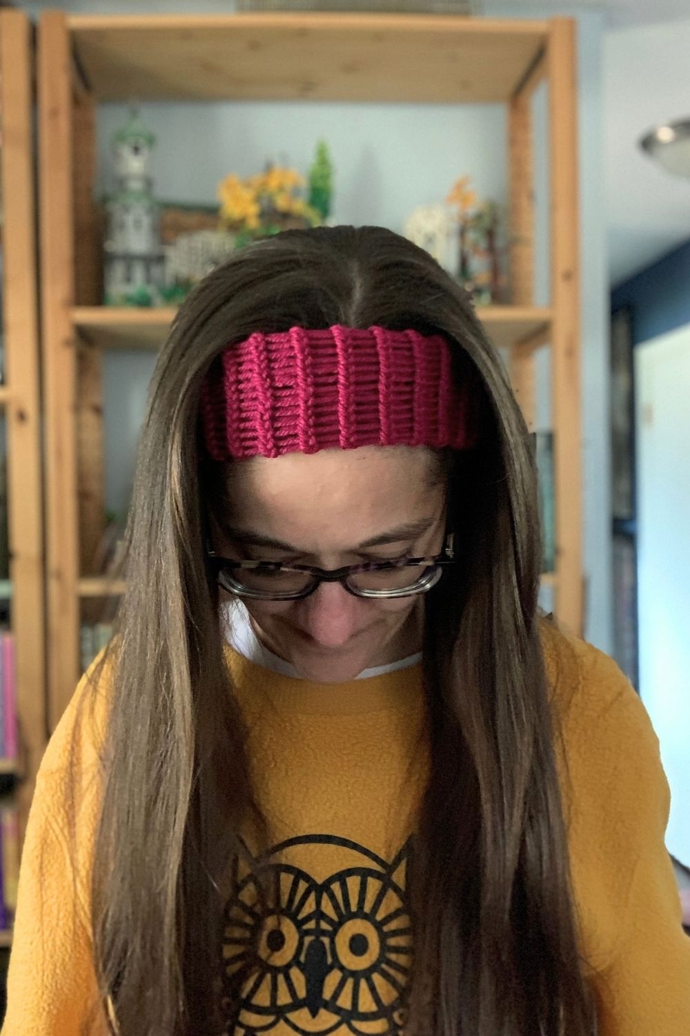 A woman with long hair up in a ponytail wearing a purple loom knit headband.