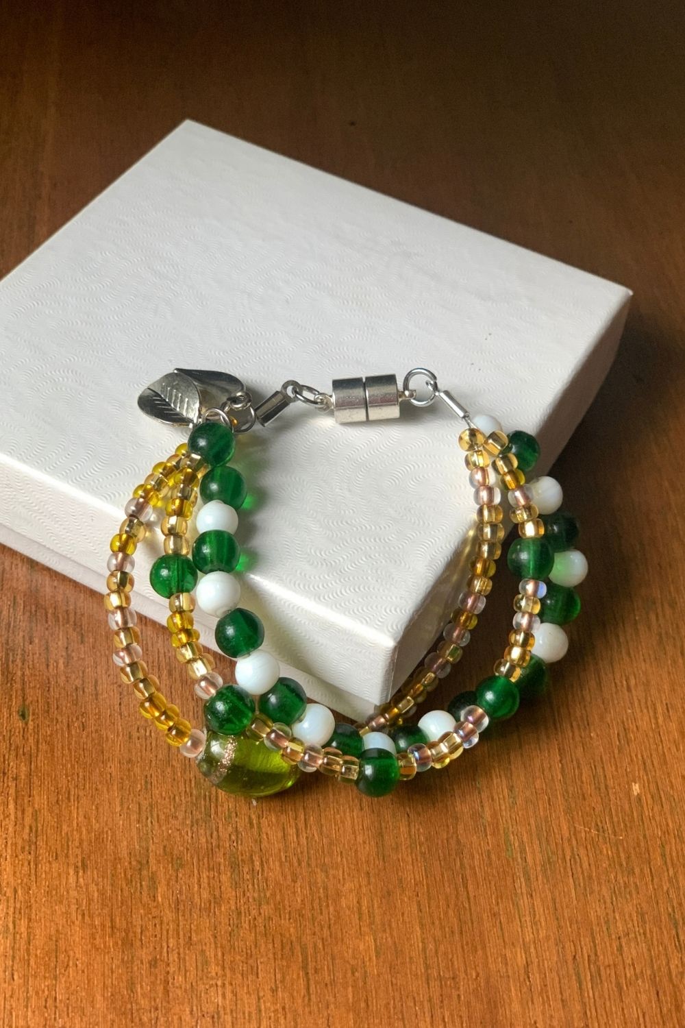 A 3-strand handmade bracelet white green, white, and gold beads.
