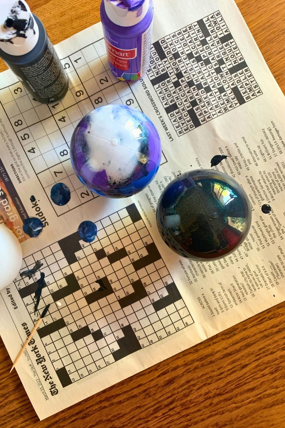 Ball ornaments filled with paint turned upside down to drip onto newspaper.