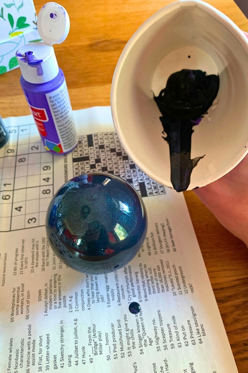 Pouring mixed black paint into a clear plastic ball.