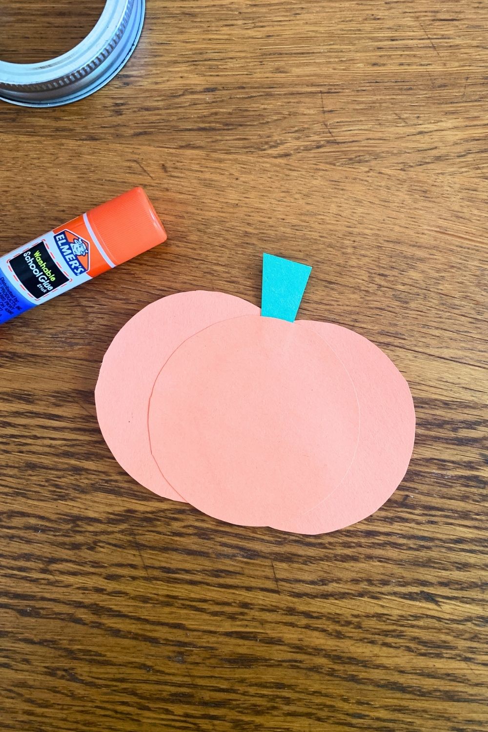 An orange construction paper pumpkin with a green stem.