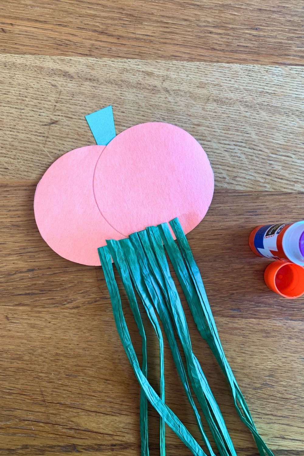 Green raffia strips glued to the back of an orange paper pumpkin.