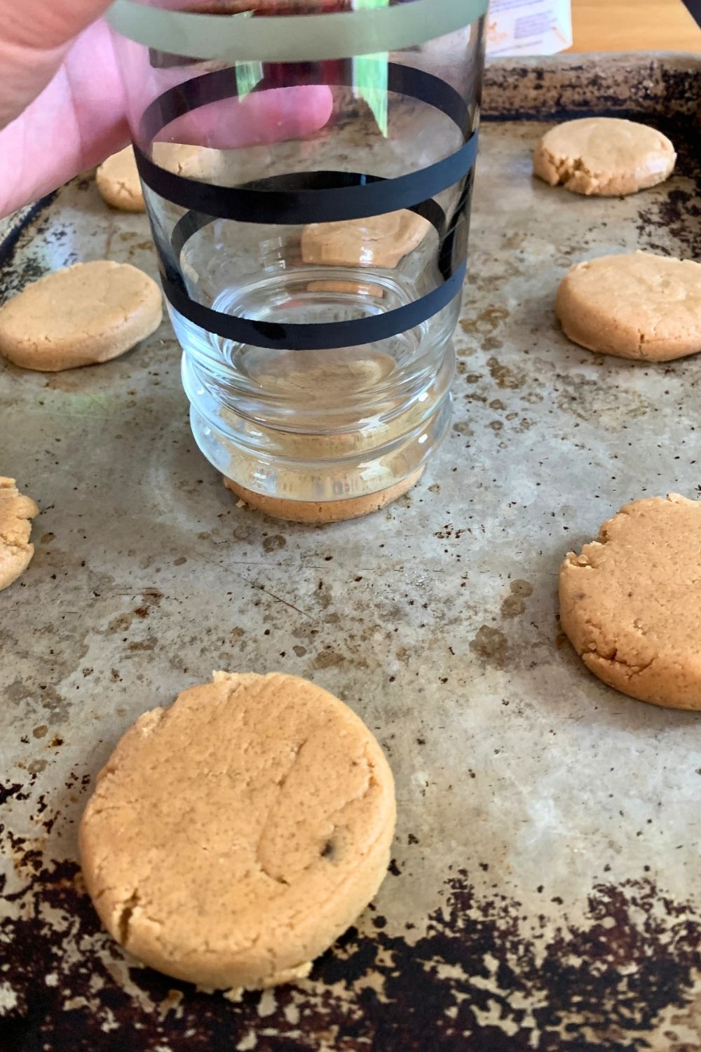 Using a drinking glass to flatten cookie dough balls.