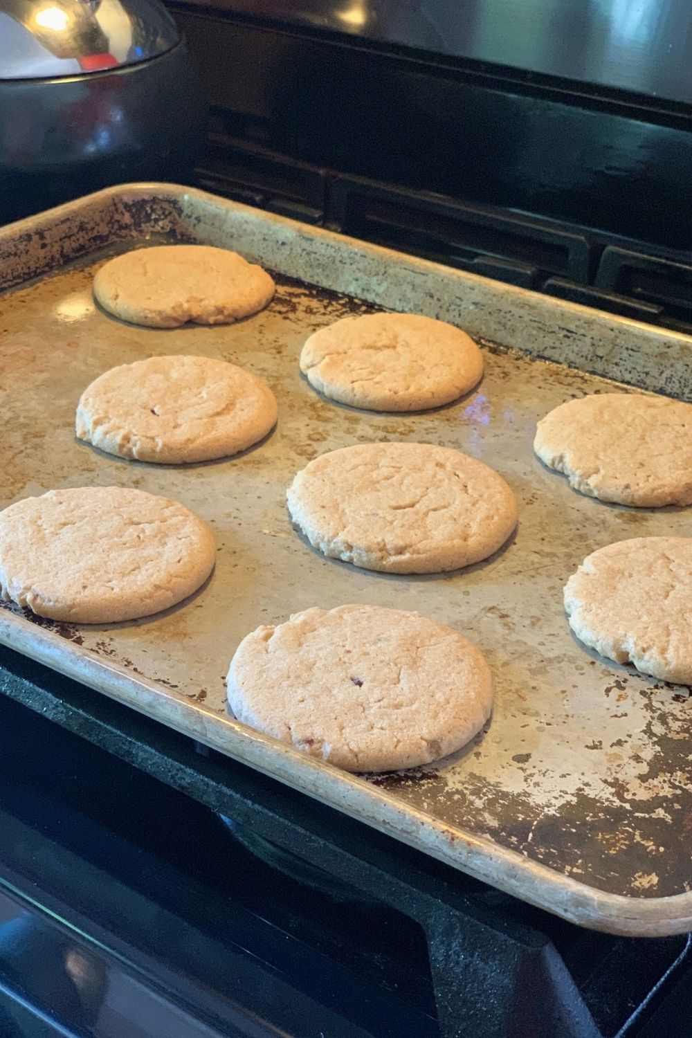 Smooth, light brown peanut butter cookies on a metal baking sheet.