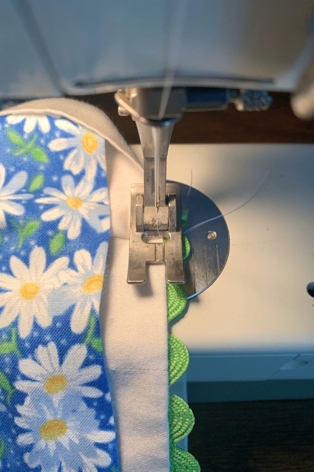 Sewing green rick rack under the edge of a white pillowcase.