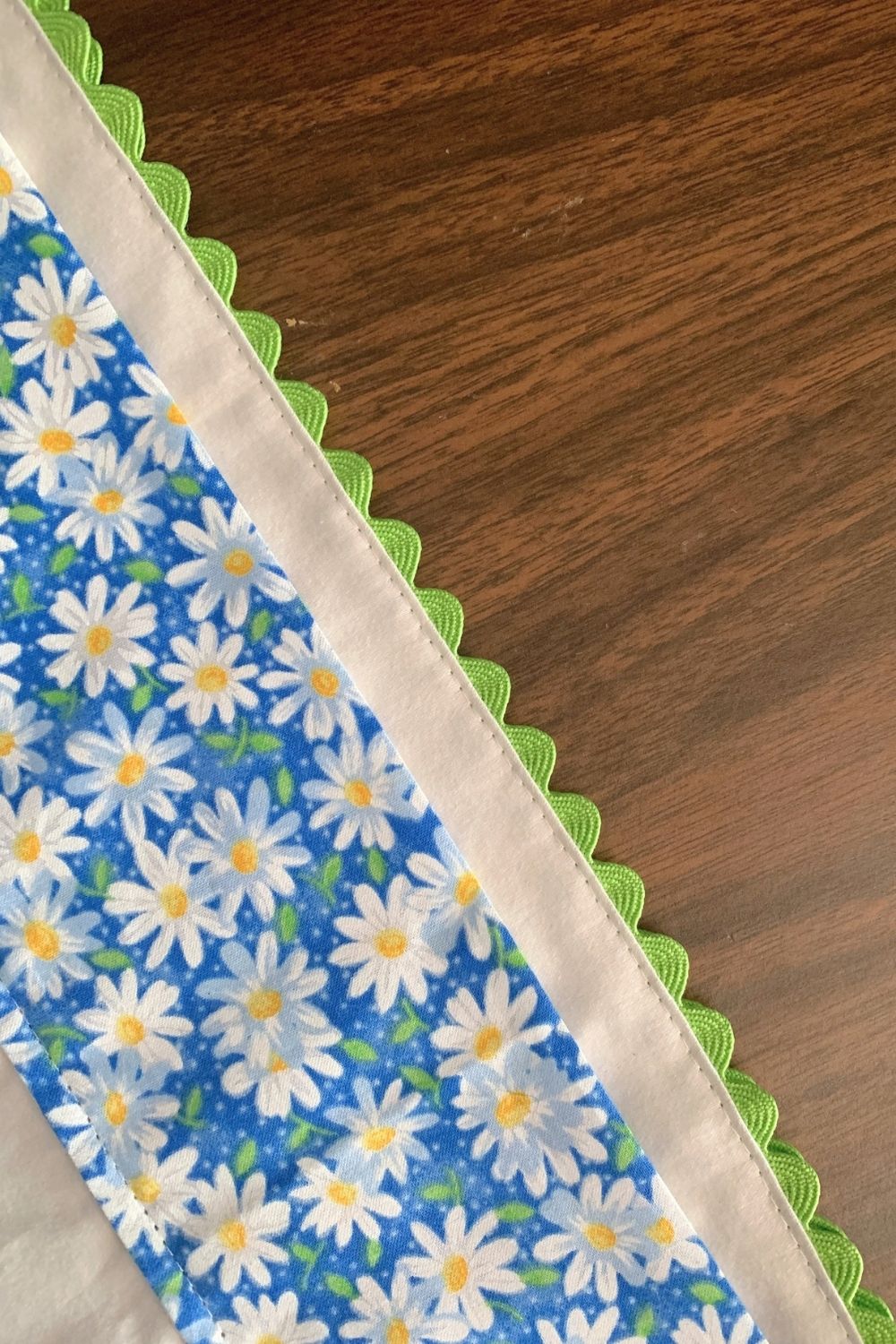 Green rick rack sewn to the edge of a white pillowcase.