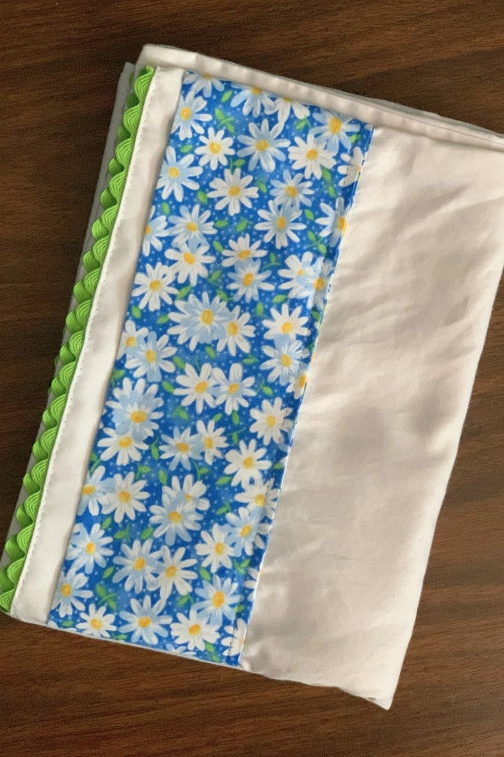 A white pillowcase with a blue and white daisy fabric stripe and green rick rack edge.