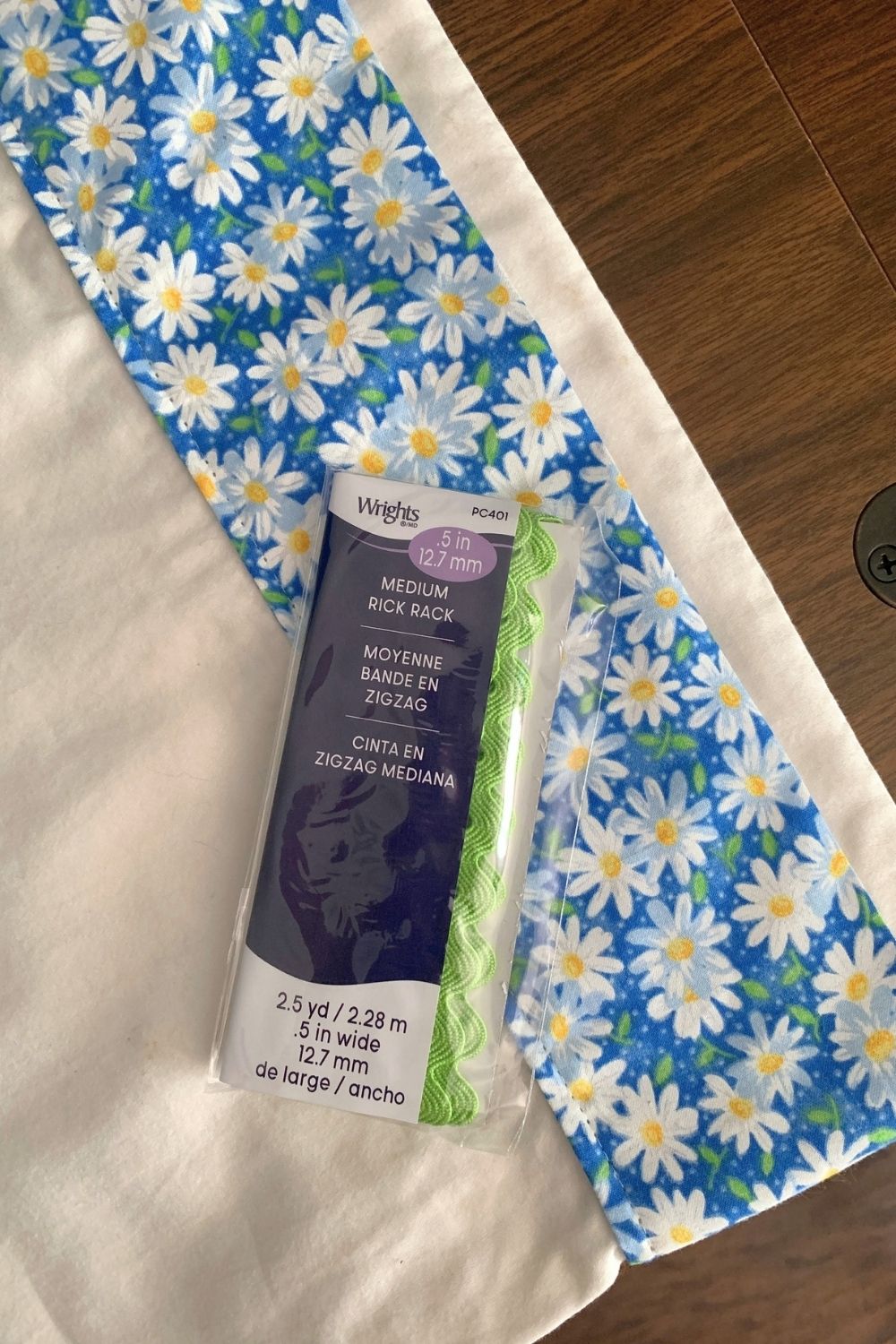 A package of bright green rick rack on top of a white pillowcase with blue daisy fabric trim.