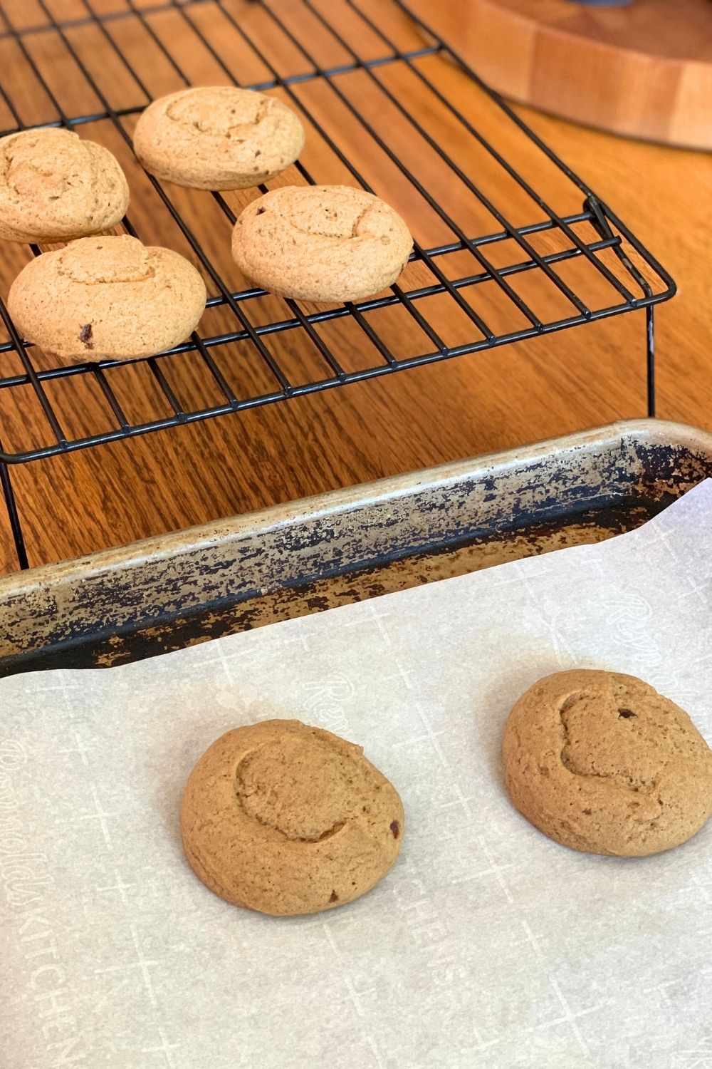 Pumpkin spice sugar cookies on a baking sheet beside others on a cooling rack.