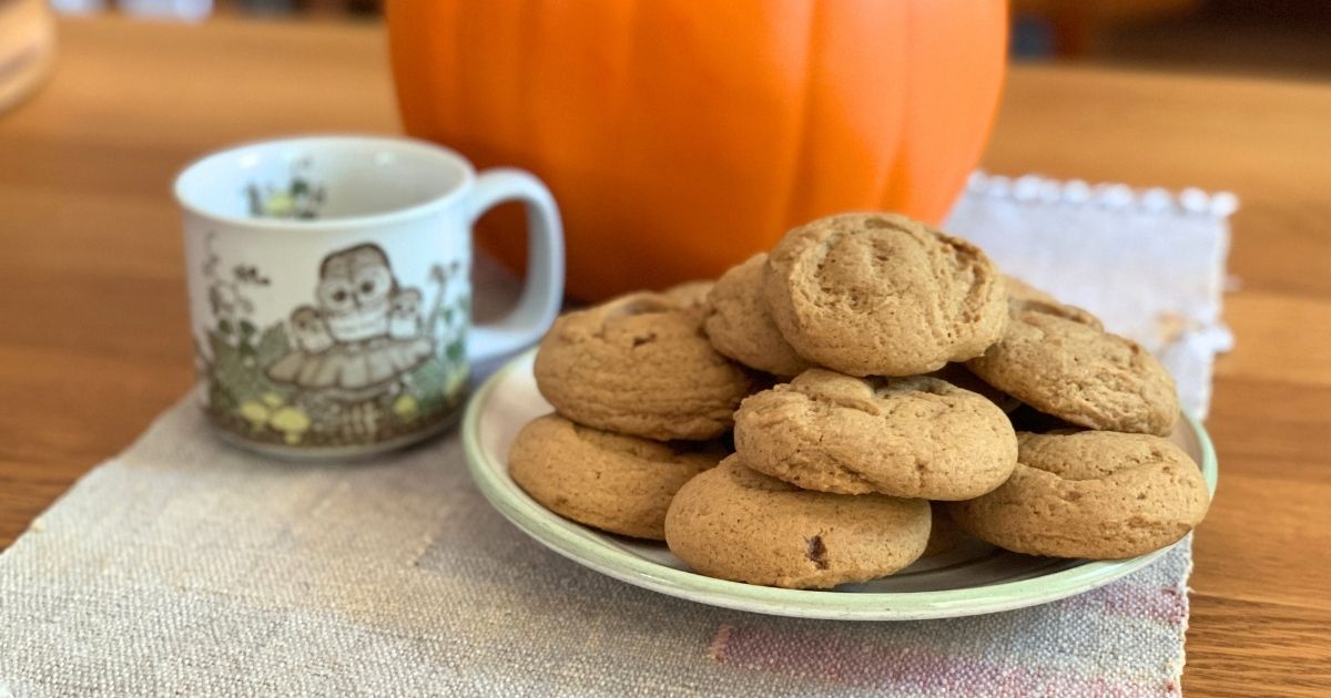 A plate of golden brown pumpkin spice sugar cookies beside a mug of coffee.