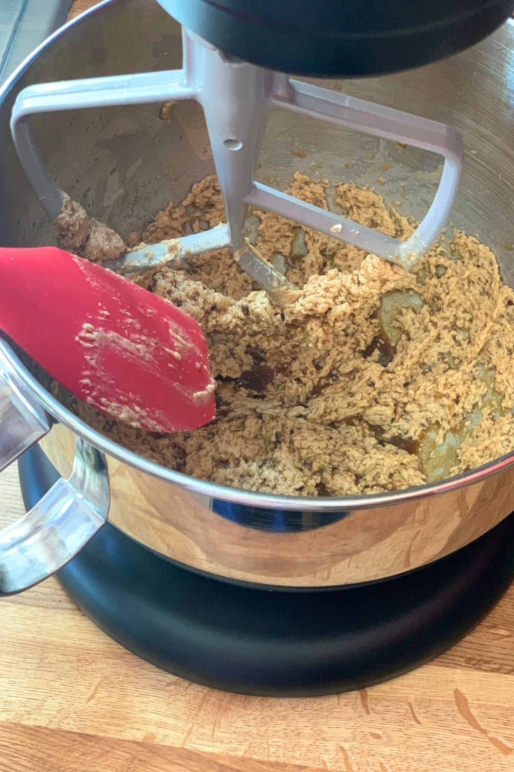 Adding milk and vanilla to cookie dough in a stand mixer.