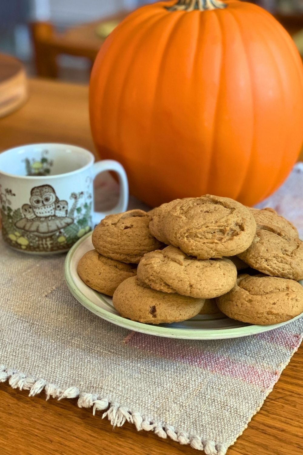 A plate of golden brown pumpkin spice sugar cookies beside a mug of coffee.